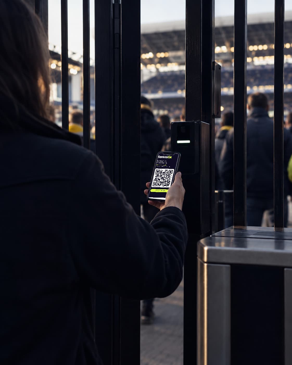 A fan holding up their Fantastix wallet pass to the reader at a stadium gate