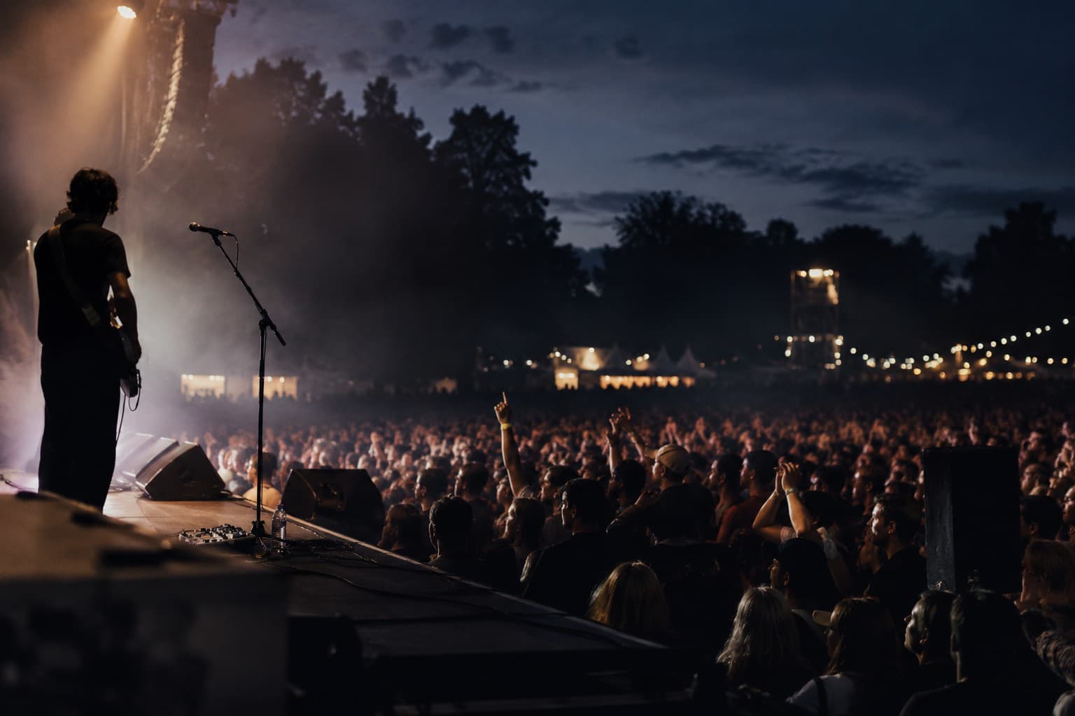 A festival crowd at night seen from the side of the stage